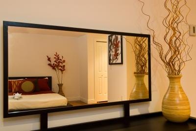 The reflection of a bedroom in a rectangular mirror.