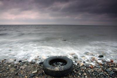 Old tire rests on the coastline in England