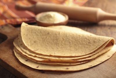 Stack of tortillas on a cutting board.