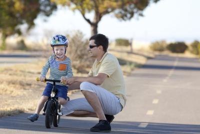 Boy with father learning to ride bicycle