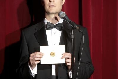 Man in tuxedo announcing award recipient