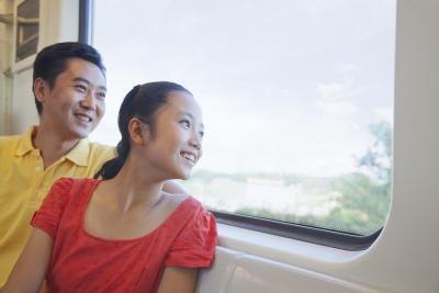 A dad and daughter look out of a subway window together.