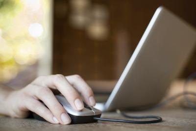 A woman clicks the mouse of her laptop.