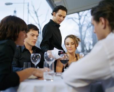 A server pours wine at a table.
