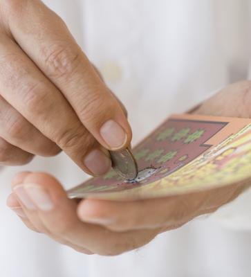 Man scratching lottery ticket with coin