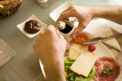 A man adds a cane sugar cube to a cup of espresso.