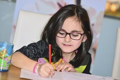 A girl writes at her desk in a colorful room. A girl writes at her desk in a colorful room.