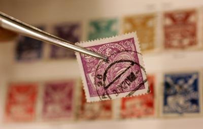 Rare stamp being held by tweezers
