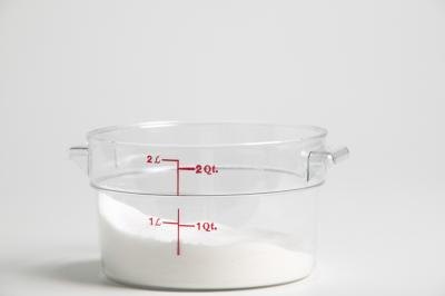 A measuring cup partially filled with cane sugar.