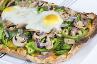 Vegetarian pizza on flat bread with two sunny side-up eggs