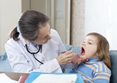 A pediatrician examines a child's throat.