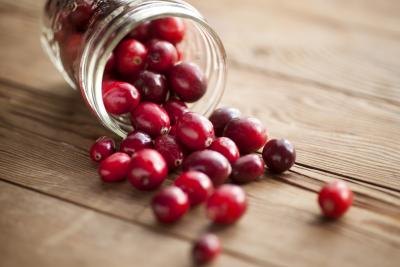 Cranberries spilling out of a jar onto a wooden table