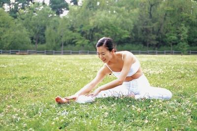 A woman stretches in a park.