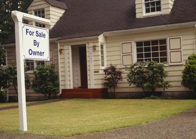 A house with a for sale sign in front. A house with a for sale sign in front.