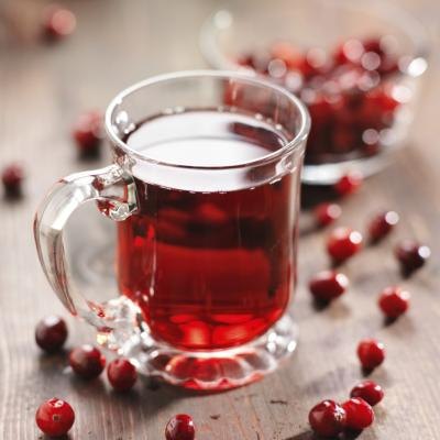 A glass cup of cranberry juice and cranberries on a wooden table