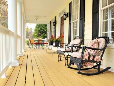 The traditional front porch of a home with light siding and dark shutters. The traditional front porch of a home with light siding and dark shutters.