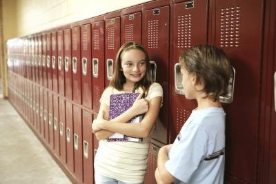 Two tweens lean on school lockers and chat.