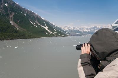 A man examines the Alaskan landscape through binoculars.