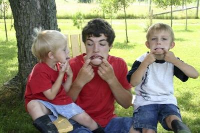 An older brother plays with his young siblings outside.