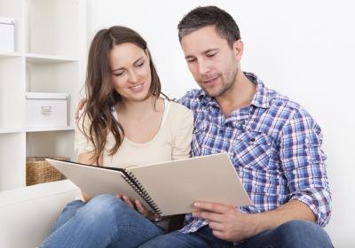 Couple sitting together on couch looking at booklet of questions