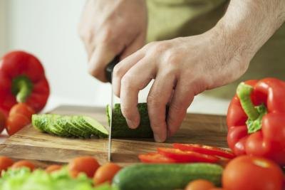 A man slices fresh vegetables on a cutting board.