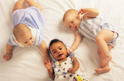 3 infants lay on a blanket together.