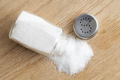 Table salt spills from open shaker