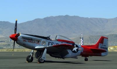 A vintage single-engine military aircraft sits on a runway.