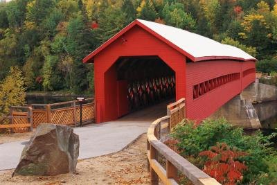 A wooden covered bridge spans a river.