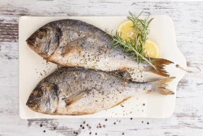 Sea bream on cutting board with lemon and rosemary