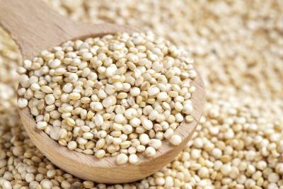 A wooden spoon filled with quinoa.