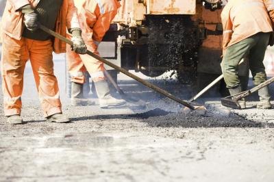 A group of workmen re-paving a road A group of workmen re-paving a road