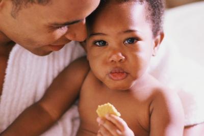Dad cuddling a toddler eating a snack