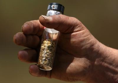 Gold prospector holds vial of gold flakes
