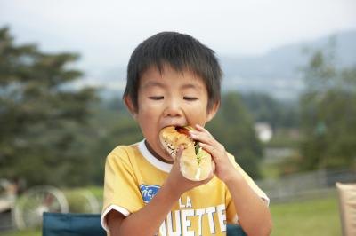 Young boy eating a hotdog.