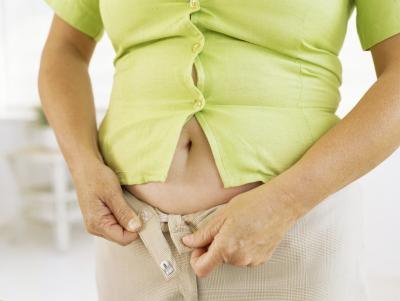 Mid-section view of a woman fastening her pants.