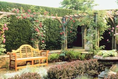 Climbing roses on an arbor over a bench enhance the garden setting.