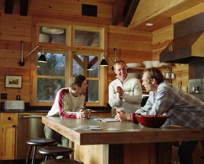 Three men talk at a kitchen island in a small kitchen.