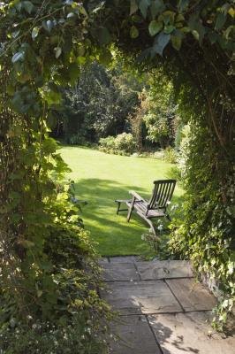 A foliage covered-arbor is charming as a gateway to the garden.