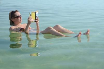 Woman reads a book while floating in the Dead Sea