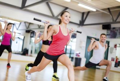 A group of men and women exercise together using barbells
