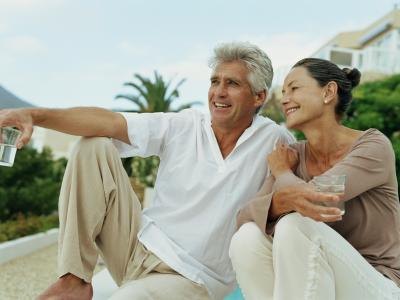 A mature couple is sitting outside smiling. A mature couple is sitting outside smiling.