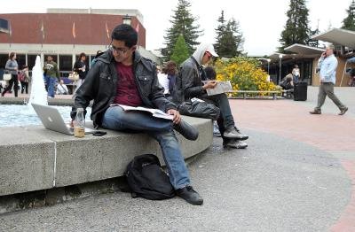 A college student working on a class assignment outside on campus. A college student working on a class assignment outside on campus.