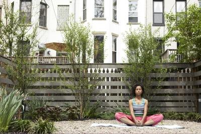 A young woman sits in bound angle pose on an urban patio.