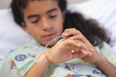 A girl looks at her IV in a hospital bed.