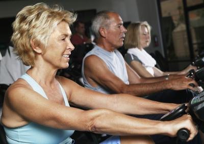 Mature people on stationary bikes at the gym.