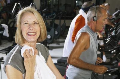 A mature woman is finishing up her workout on the treadmill.