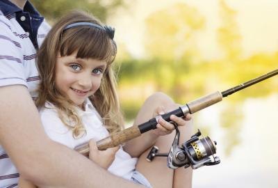 A young girl snuggles with her father while fishing at the lake.
