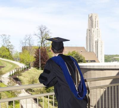 Doctorial graduate looking over the Cathedral of Learning at the University of Pittsburgh