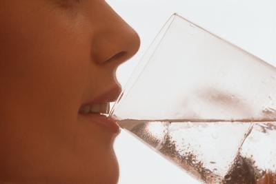 A woman drinks a glass of water.